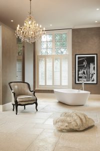 Luxueuze badkamer met kroonluchter bad en fauteuil